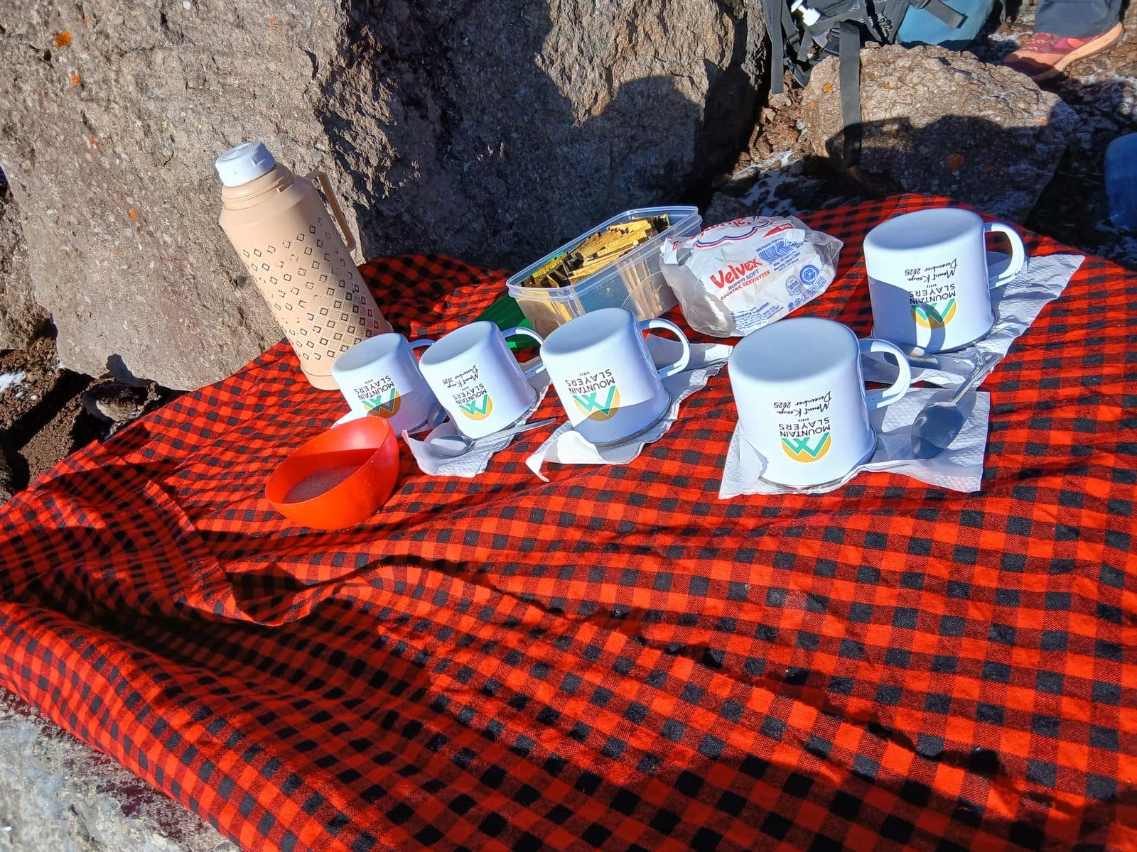 Tea and snacks laid out on a red checked Maasai shuka on the mountain