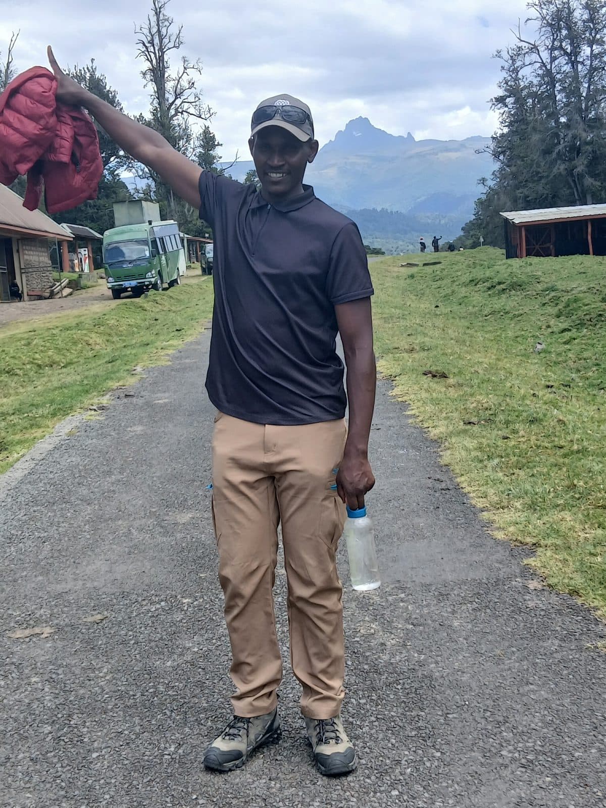 Smiling guide on a park road with Mount Kenya's peaks behind