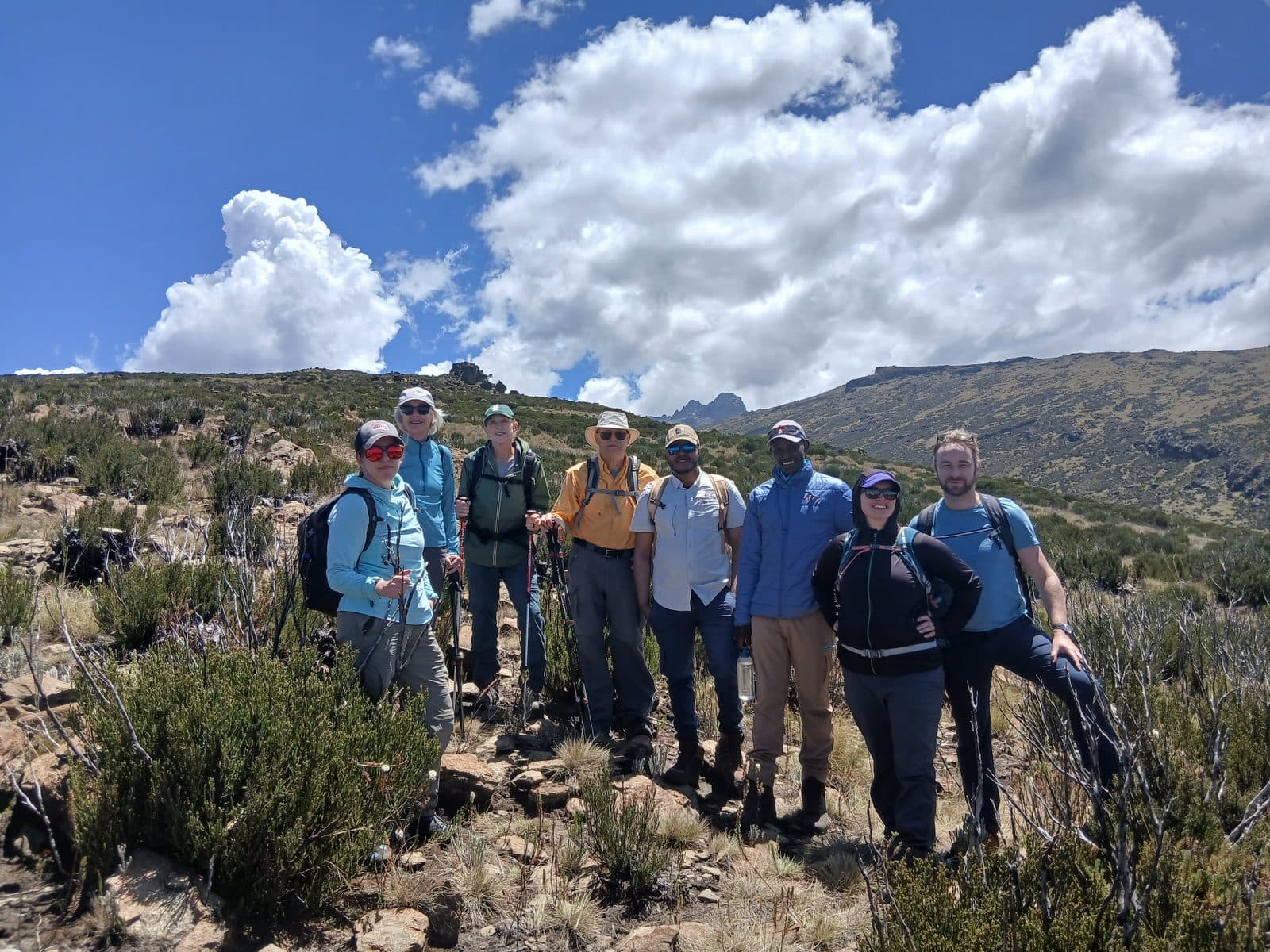 Group of trekkers posing on the moorland under big white clouds