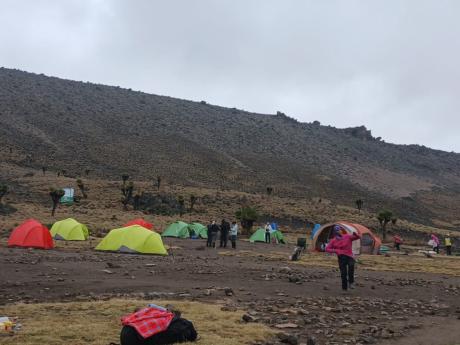Tents spread across a valley camp as trekkers arrive