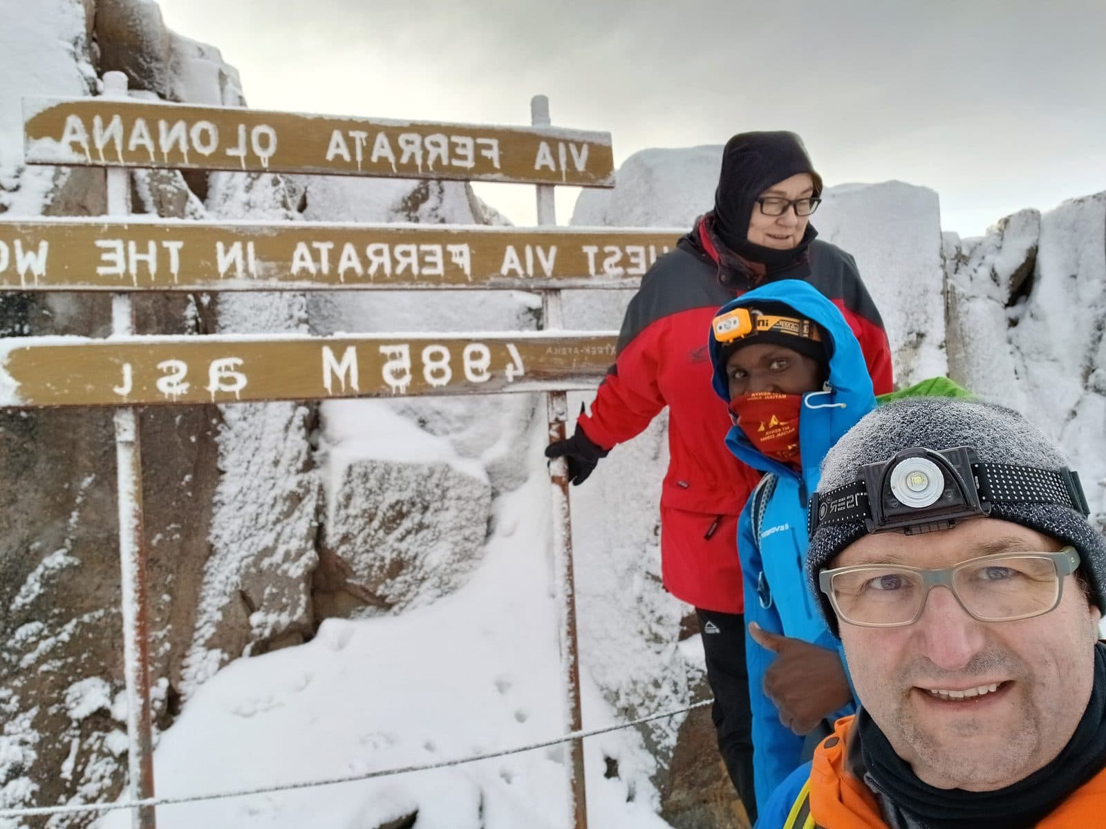 Trekkers at the via ferrata sign at 4,985 m on Point Lenana, Mount Kenya