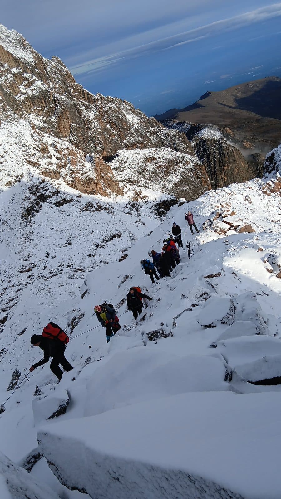 Trekkers descending a snowy ridge on Mount Kenya