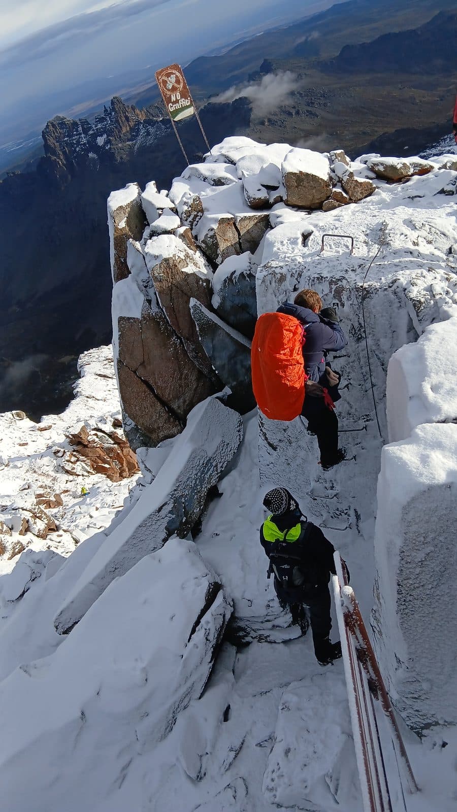 Trekkers on the snowy via ferrata ladders near Point Lenana