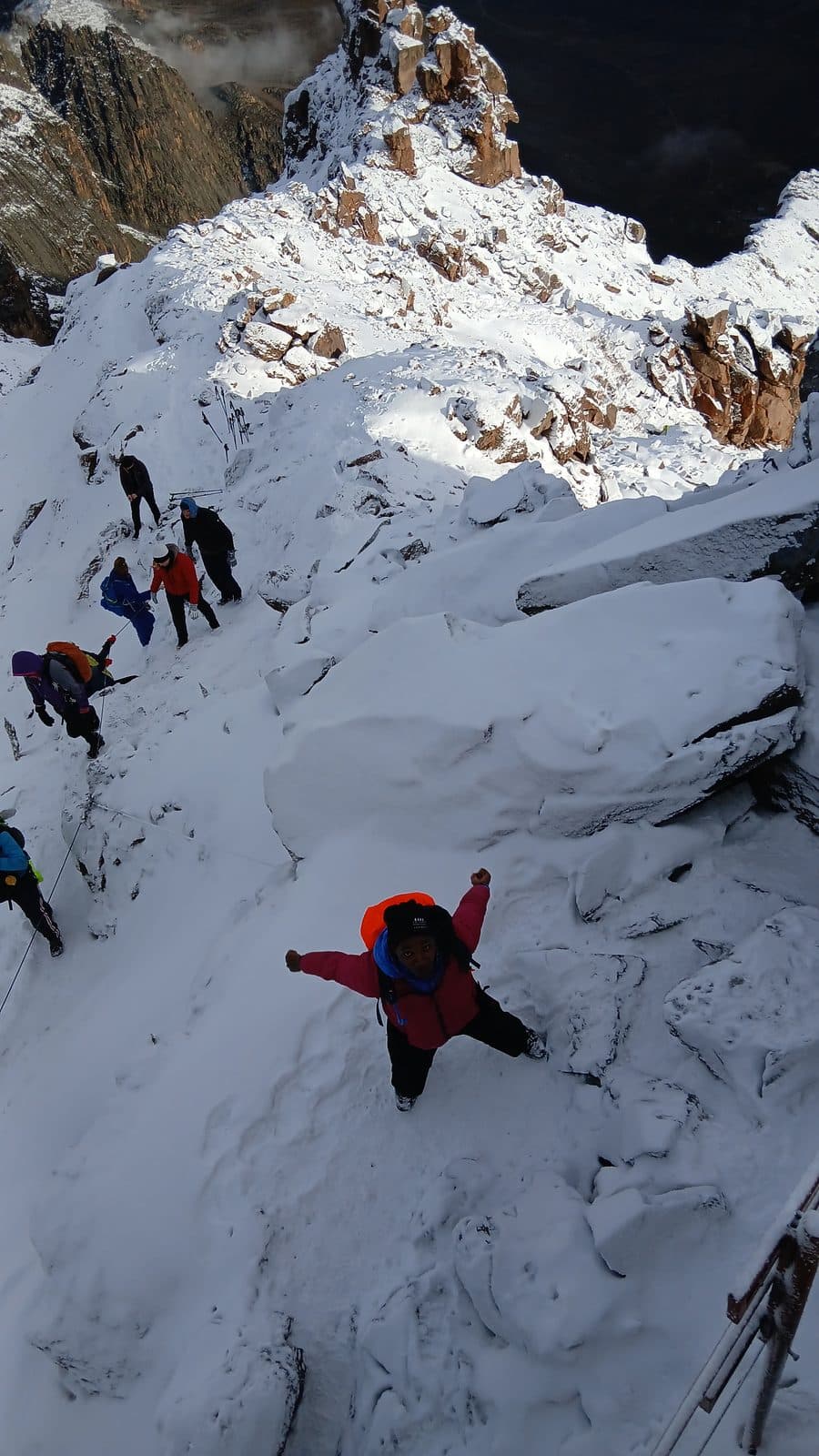 Trekkers climbing a steep snowy gully near the summit