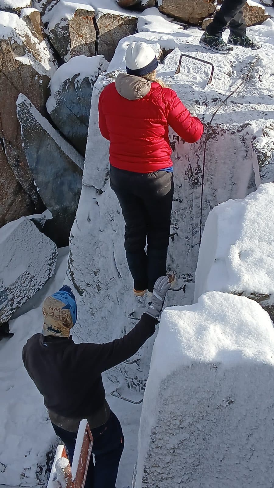Trekkers using the via ferrata to climb snowy rocks