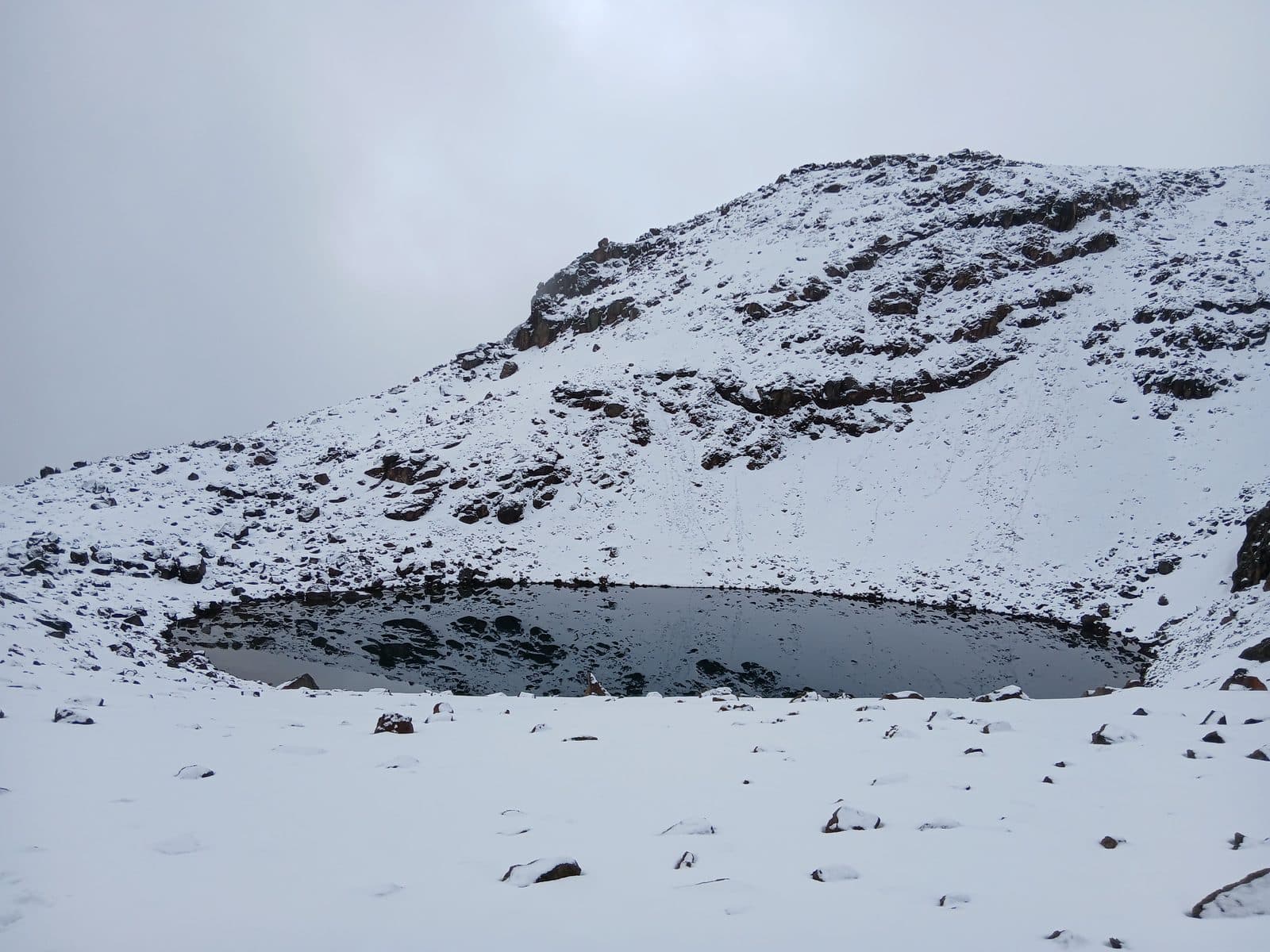 Frozen tarn in a snow-covered cirque on Mount Kenya