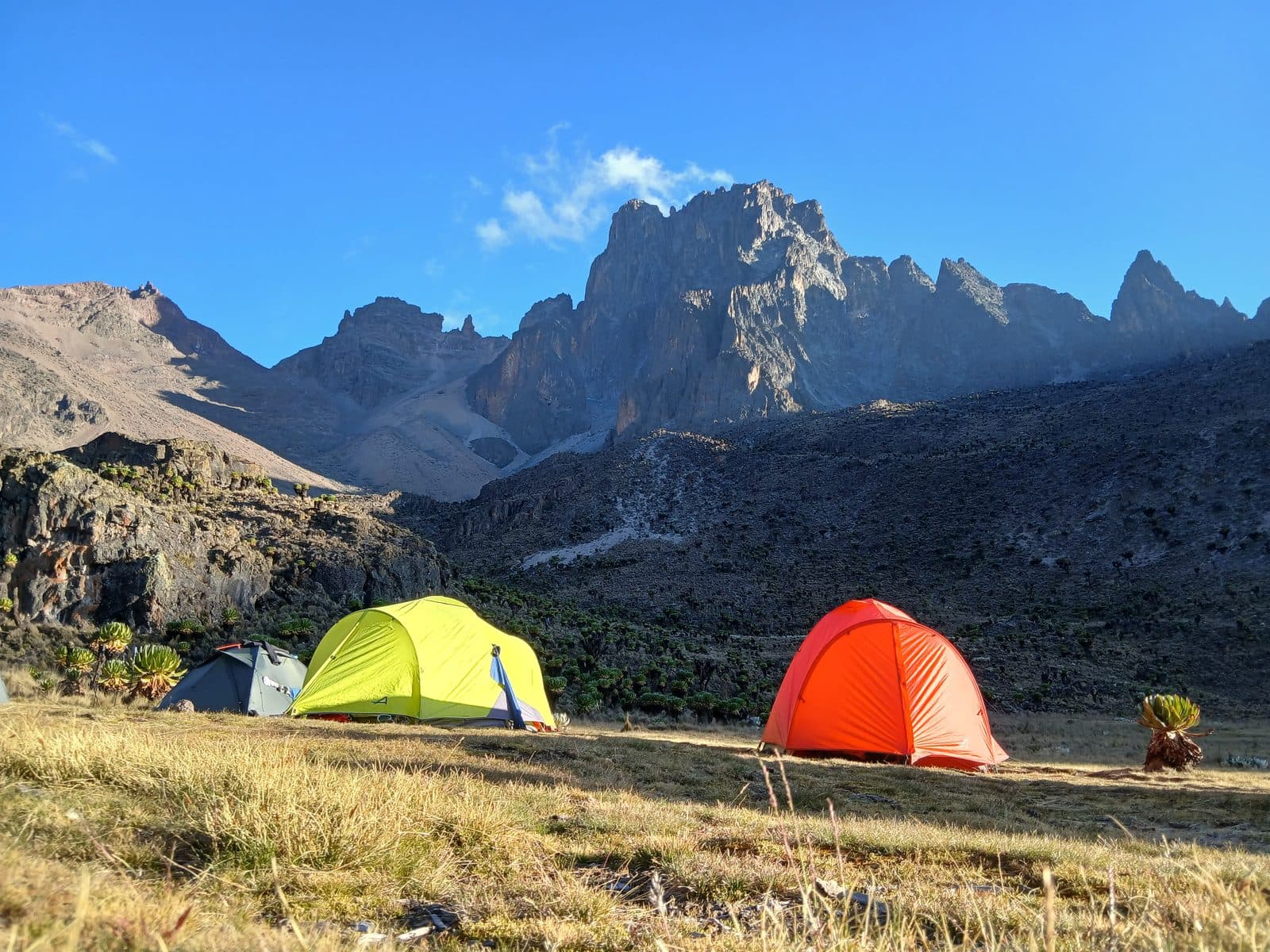 Yellow and orange tents below Mount Kenya's sunlit peaks
