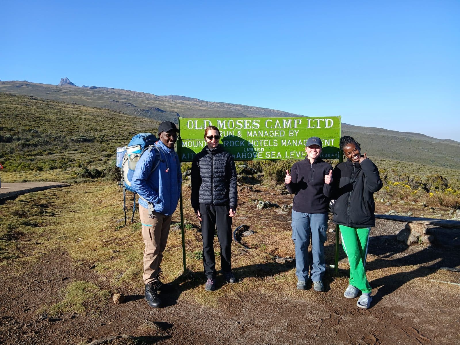 Trekkers at the Old Moses Camp sign on Mount Kenya's Sirimon route