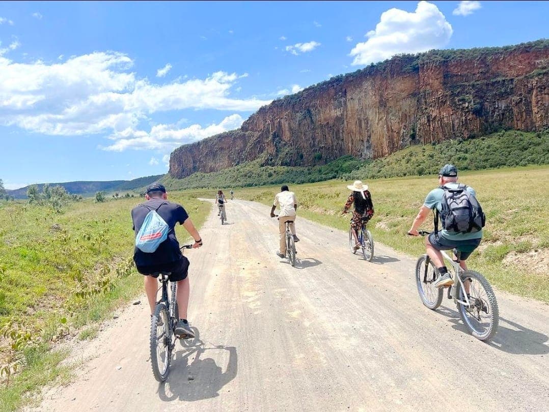 Cyclists riding between the red cliffs of Hell's Gate National Park