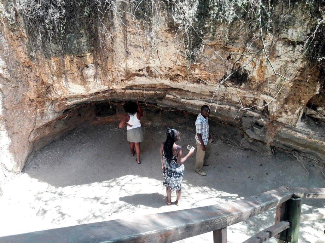 Visitors at a viewing rail below a rock overhang